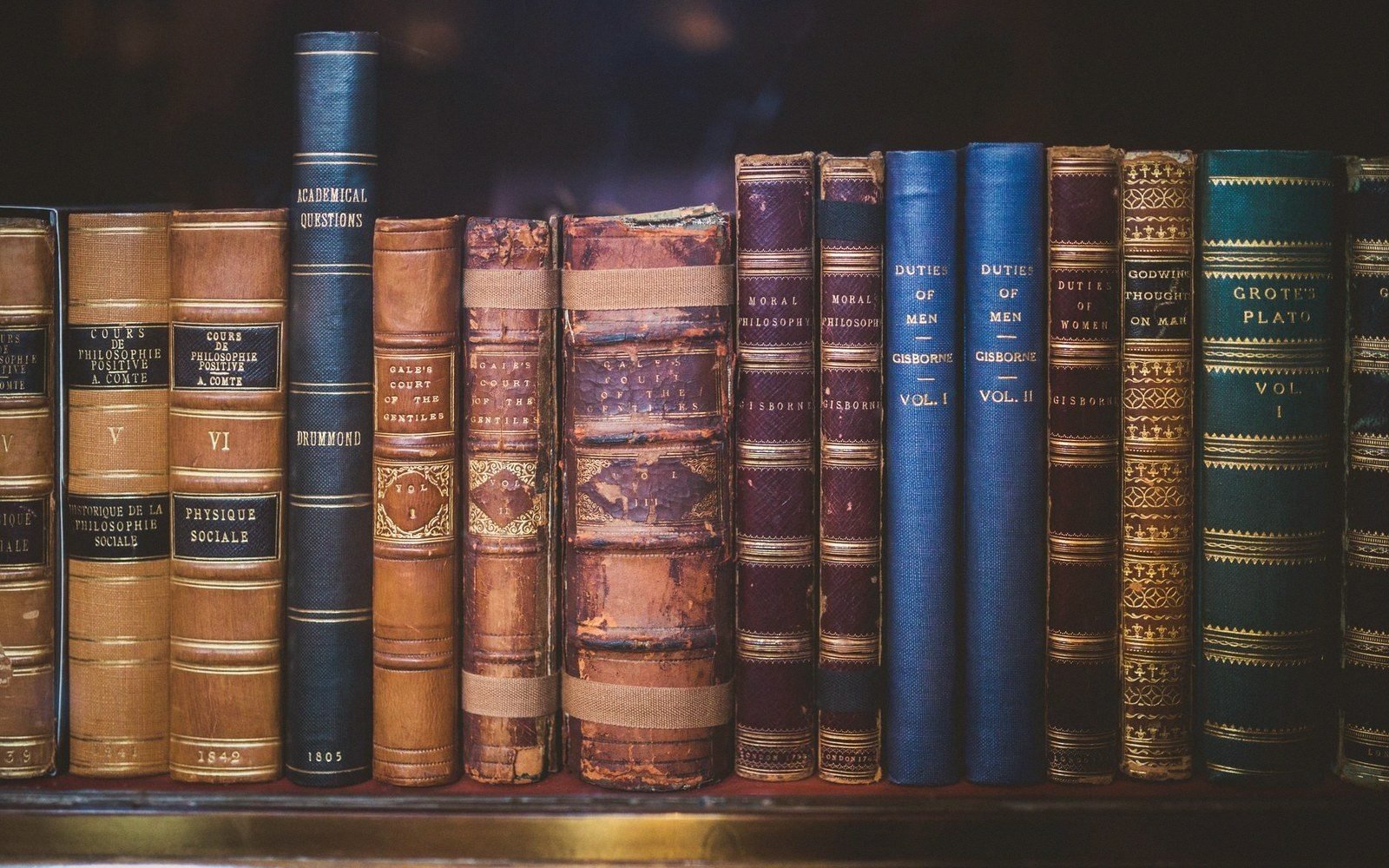 Row of antique leather-bound philosophy books with gold-lettered spines on a shelf