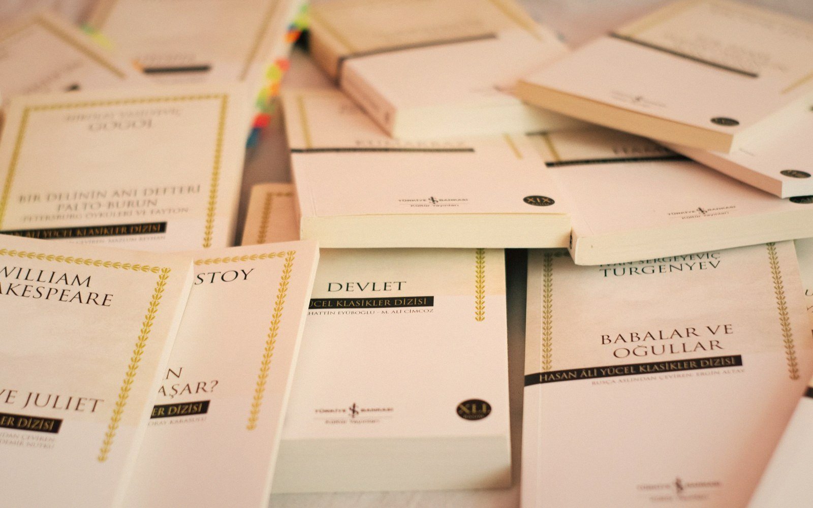 Stacks of paperback classics from the Hasan Ali Yücel series scattered on a table