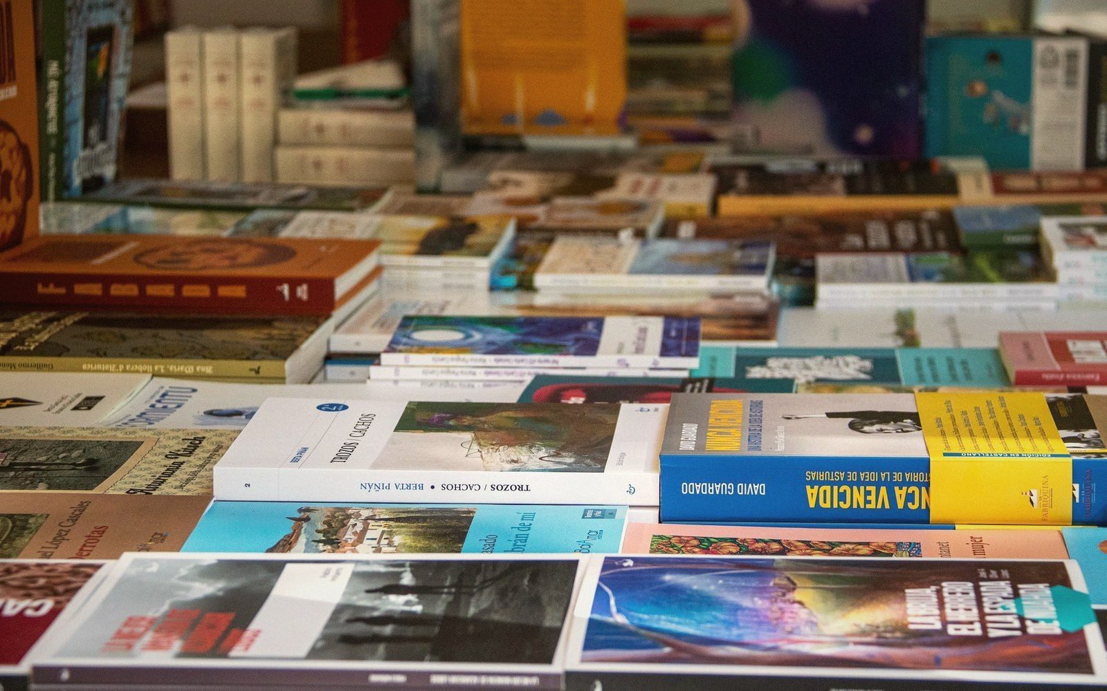 Rows of Spanish-language paperback books displayed on tables at a bookshop