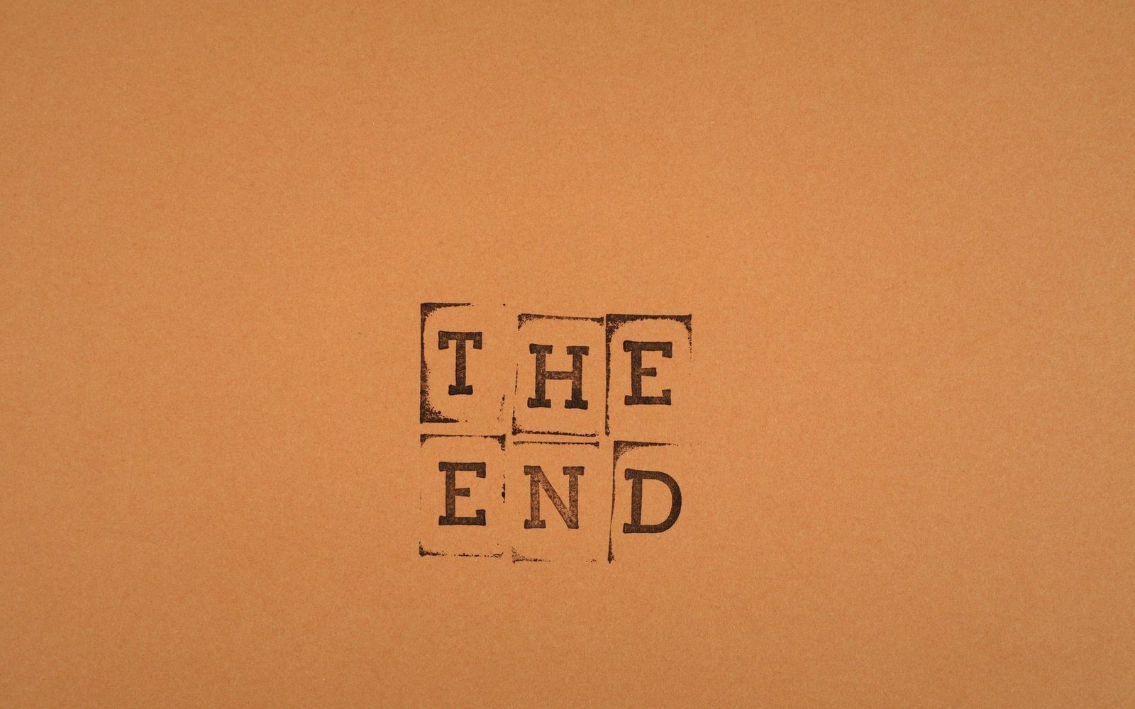 The words "the end" stamped in individual letter blocks on brown paper