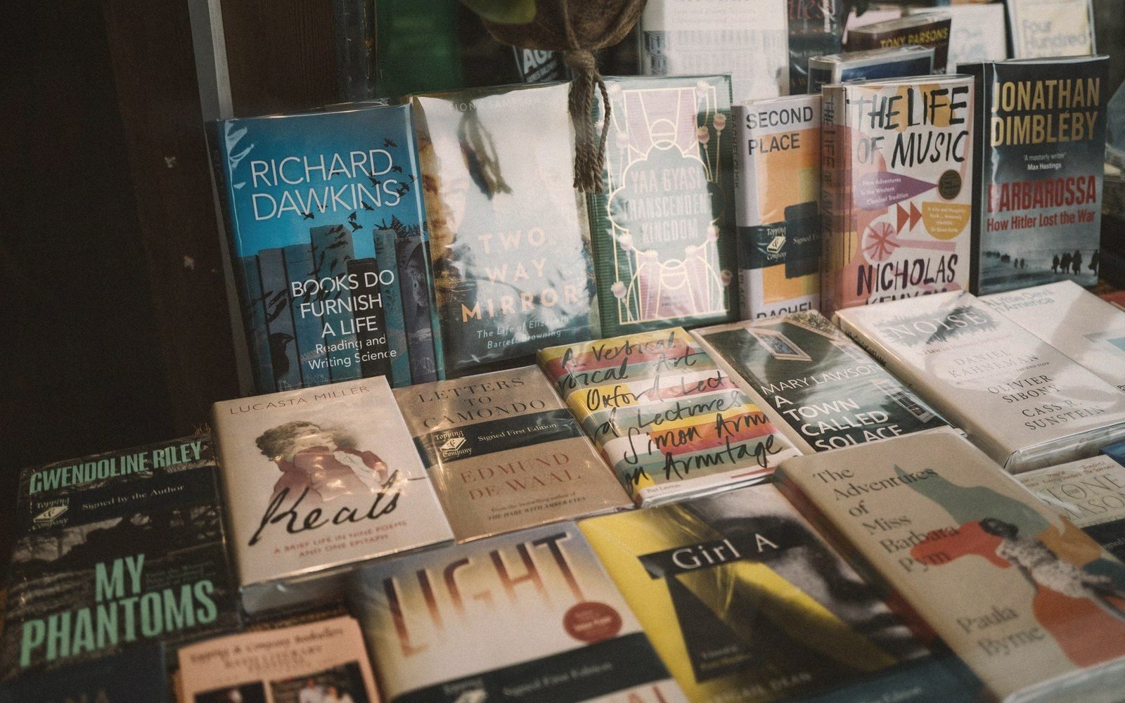 Rows of hardback books displayed in a bookshop window, including titles by Richard Dawkins and Jonathan Dimbleby